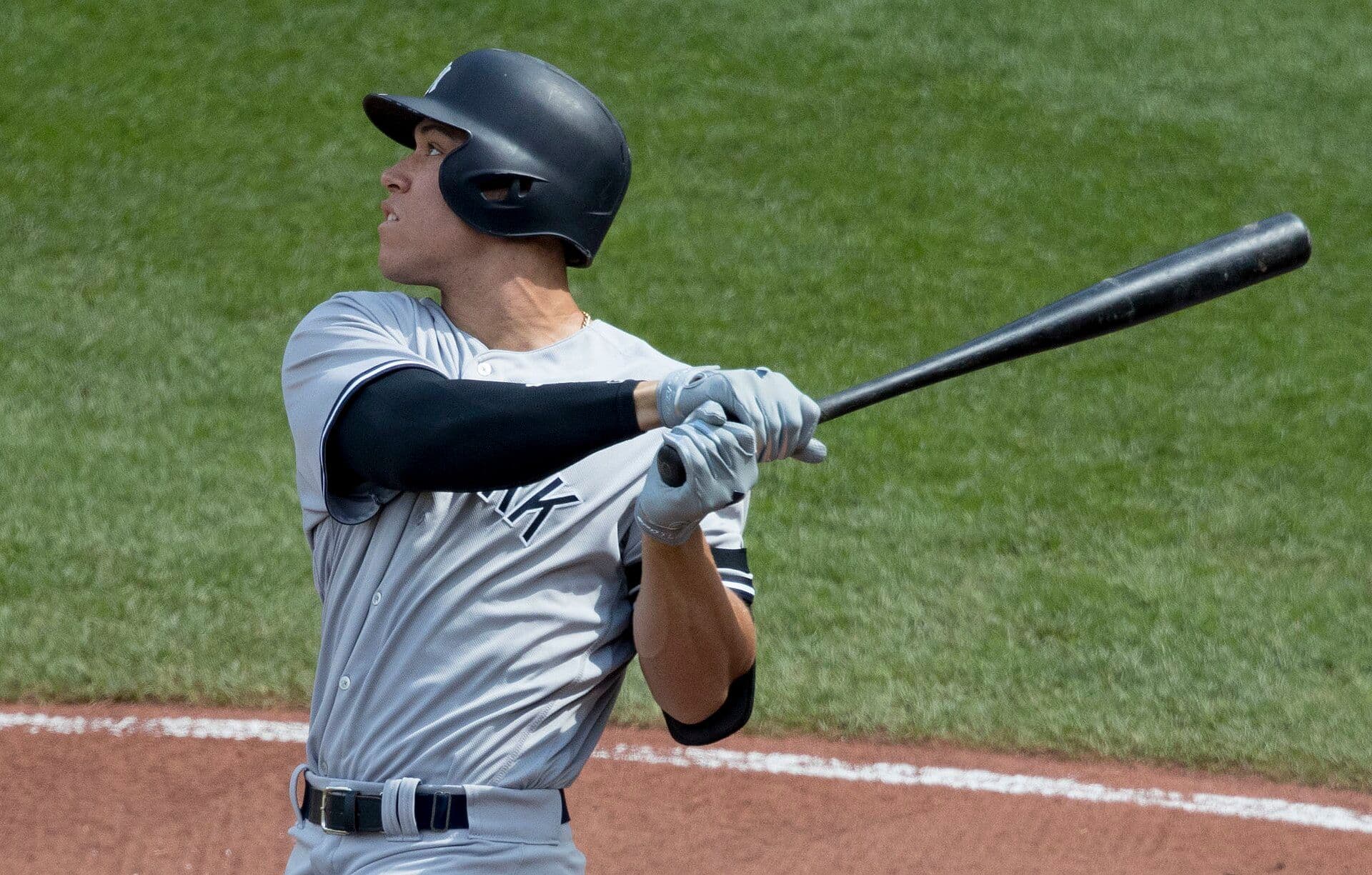 New York Yankees slugger Aaron Judge follows through on a swing in a gray road uniform.