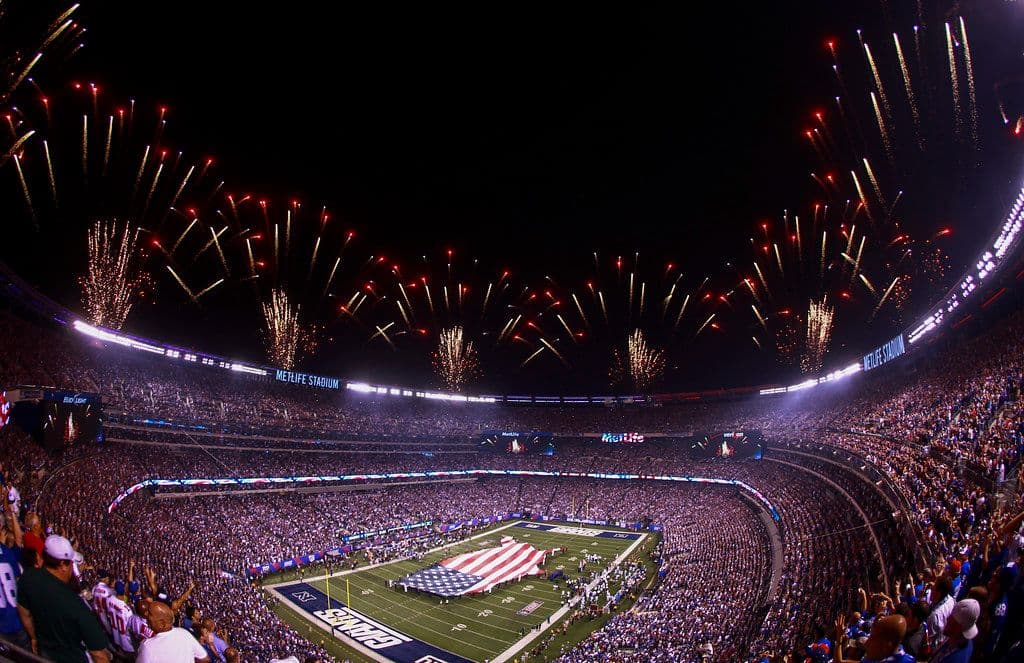 Fireworks over a packed MetLife Stadium during a nighttime pregame ceremony.
