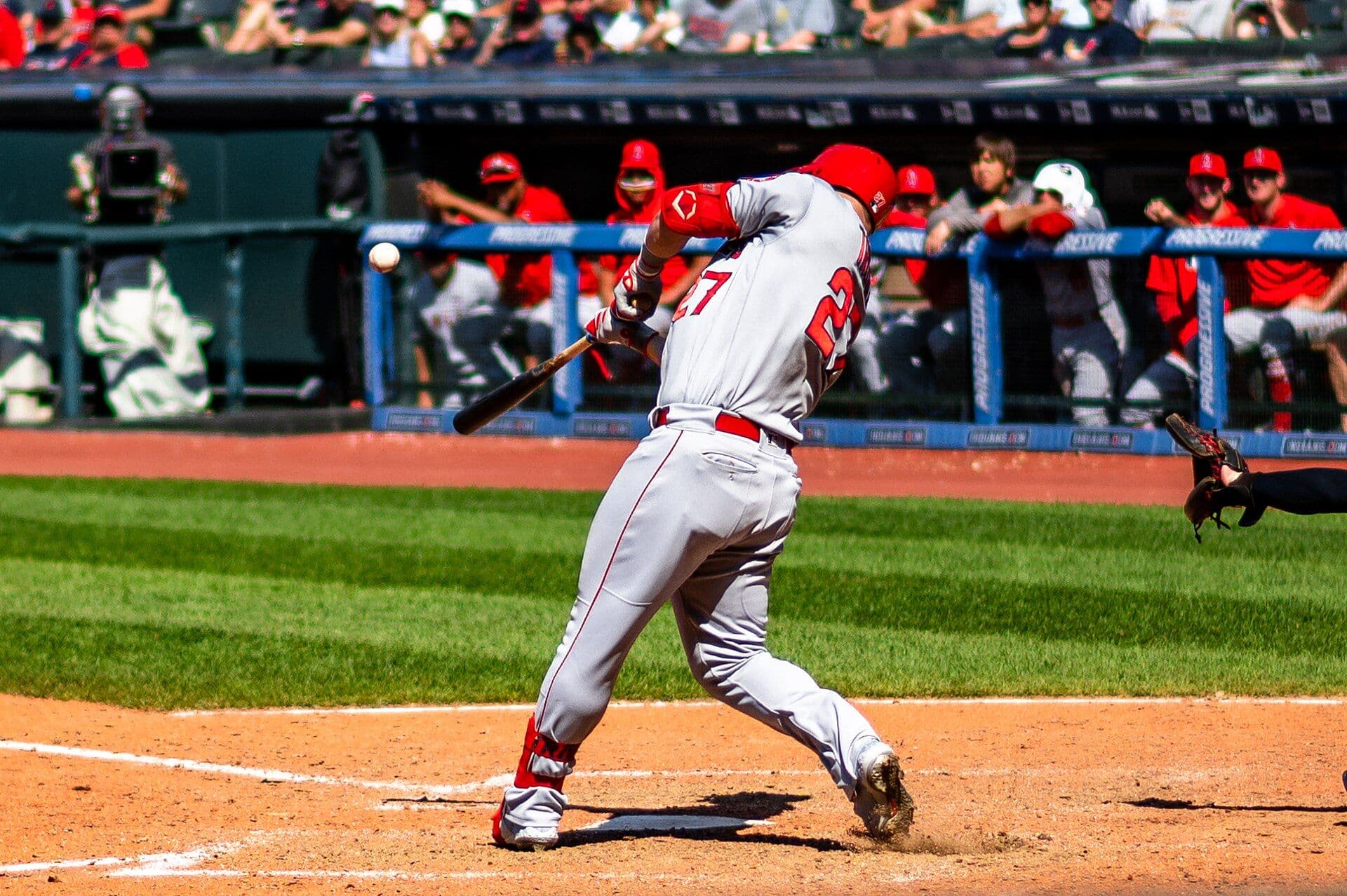 Mike Trout swings and makes contact with a pitch while wearing a gray Los Angeles Angels road uniform with number 27 on his back.