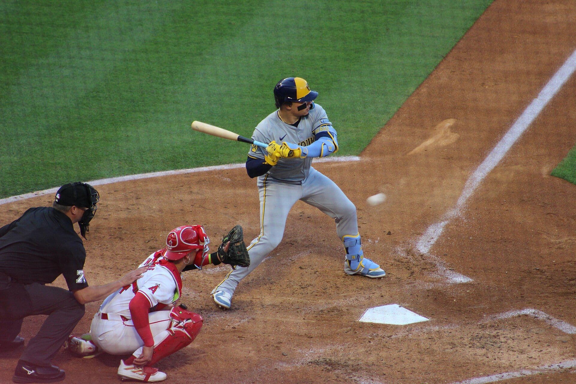 William Contreras of the Milwaukee Brewers in the batter's box wearing a gray road uniform with the Milwaukee wordmark and a navy and gold helmet.