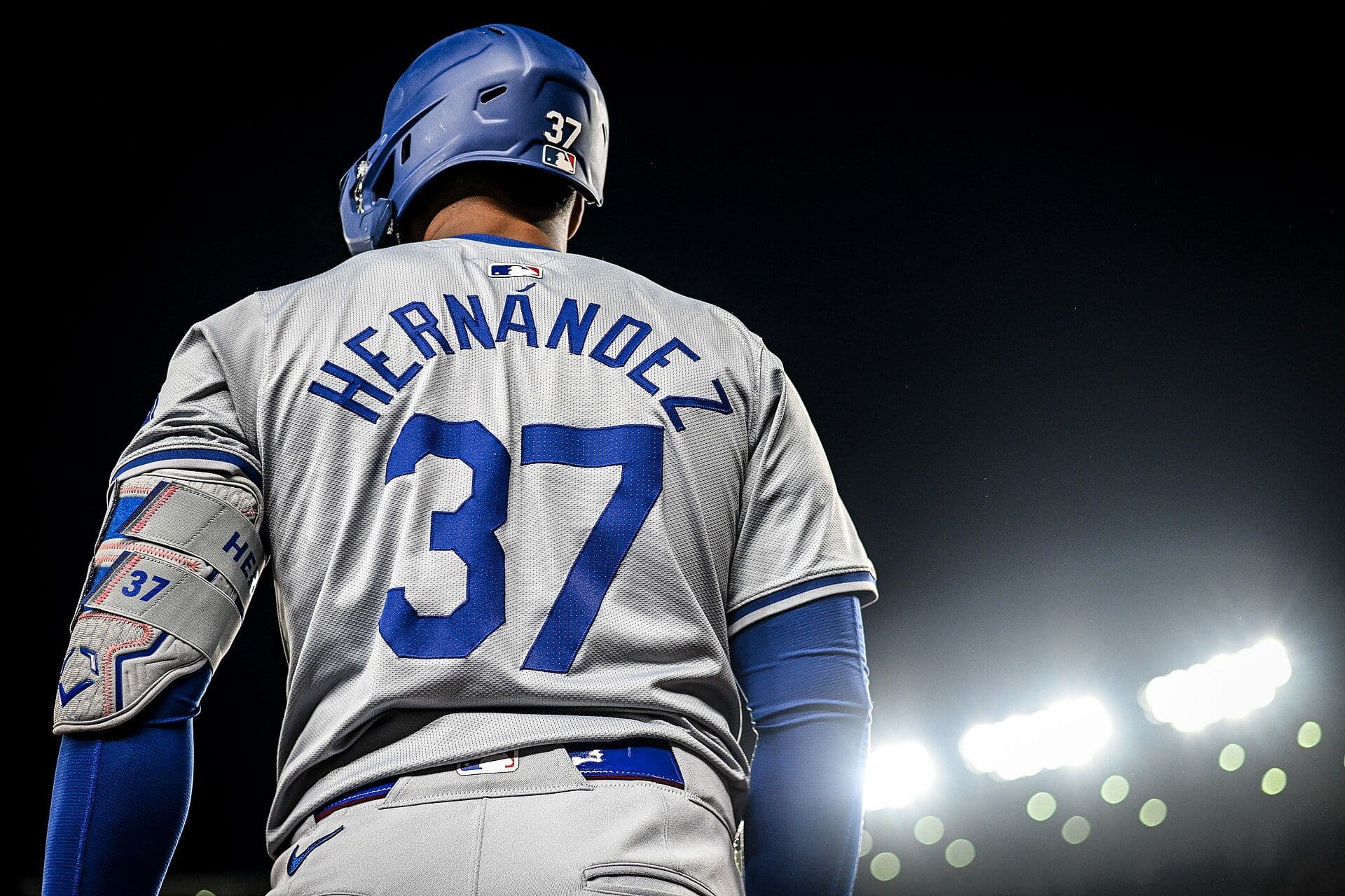 Teoscar Hernandez in a gray Los Angeles Dodgers road uniform, nameplate and number 37 visible, heading to the plate under stadium lights at night.