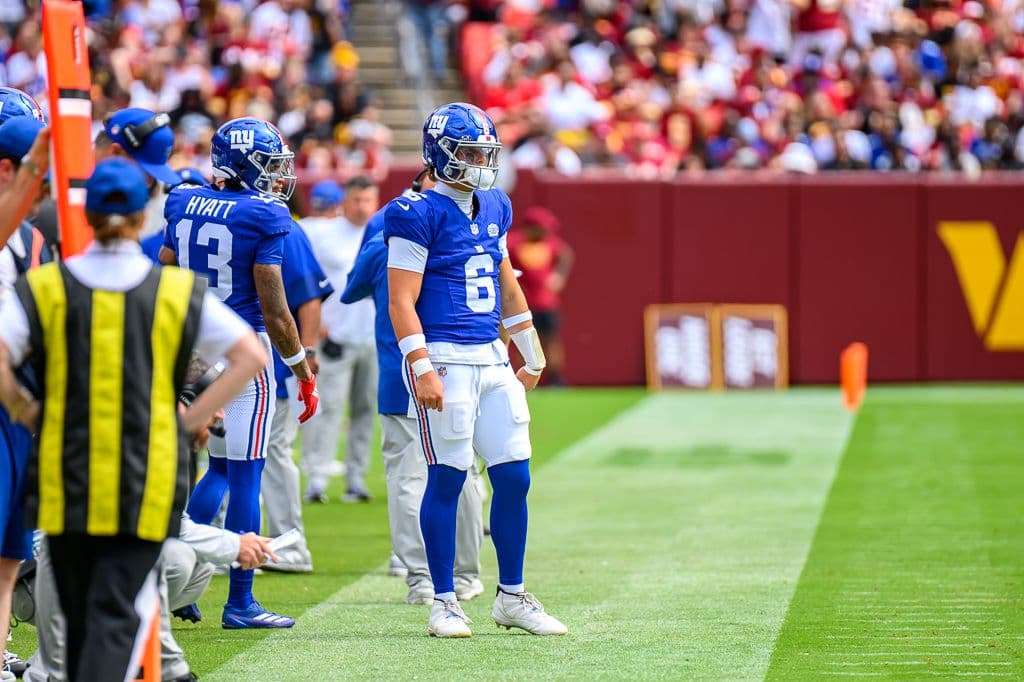 New York Giants quarterback Jaxson Dart, number 6, standing on the sideline in a blue Giants uniform during a 2025 game at Washington