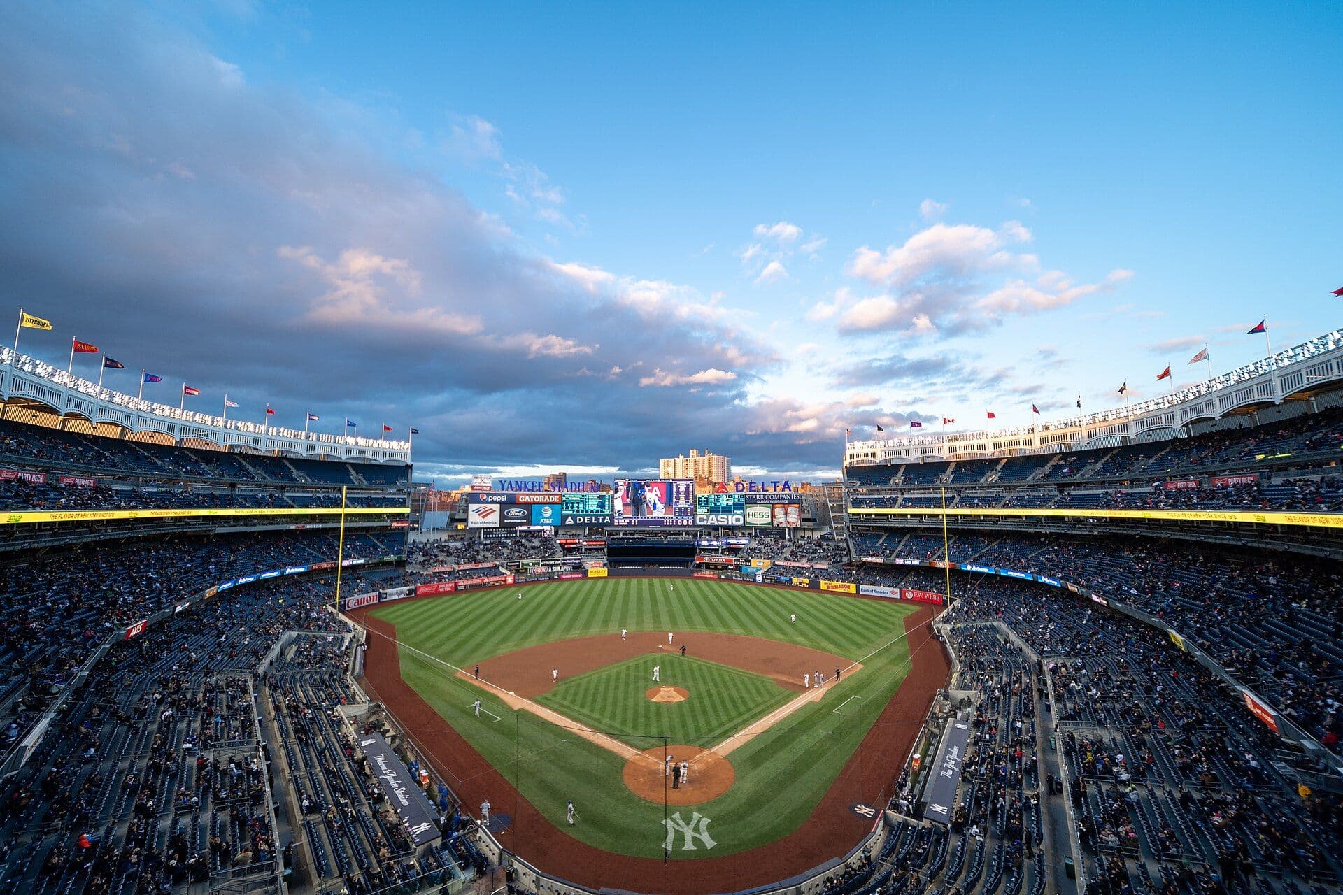 Golden-hour sunset over a Major League Baseball stadium, seen from inside the seating bowl.